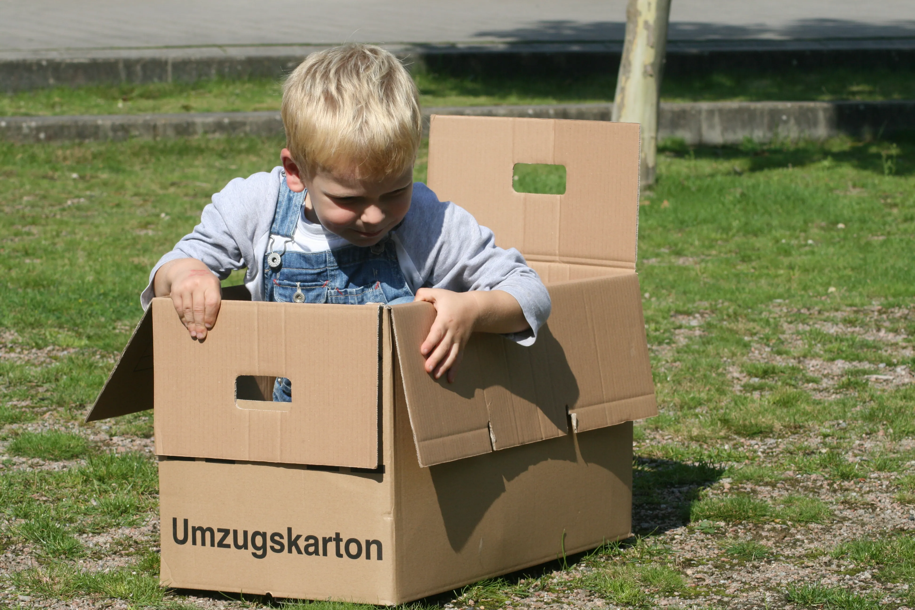 Kind spielt zwischen Umzugskartons -- Familienumzuege mit Fuhrmann